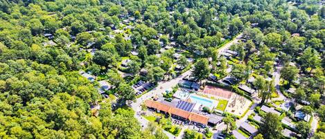 Vista aérea de una zona residencial con casas, una piscina y una cancha de tenis.