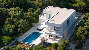 Une maison moderne à deux étages, dotée d’une piscine, d’un jacuzzi et d’un balcon.