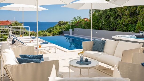 Un espace aménagé au bord de la piscine, avec vue sur la mer, comprenant des meubles d’extérieur et un jacuzzi.