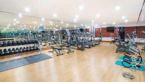 Une salle de sport équipée de divers appareils d’entraînement, notamment des tapis de course, des appareils de musculation et des poids libres.