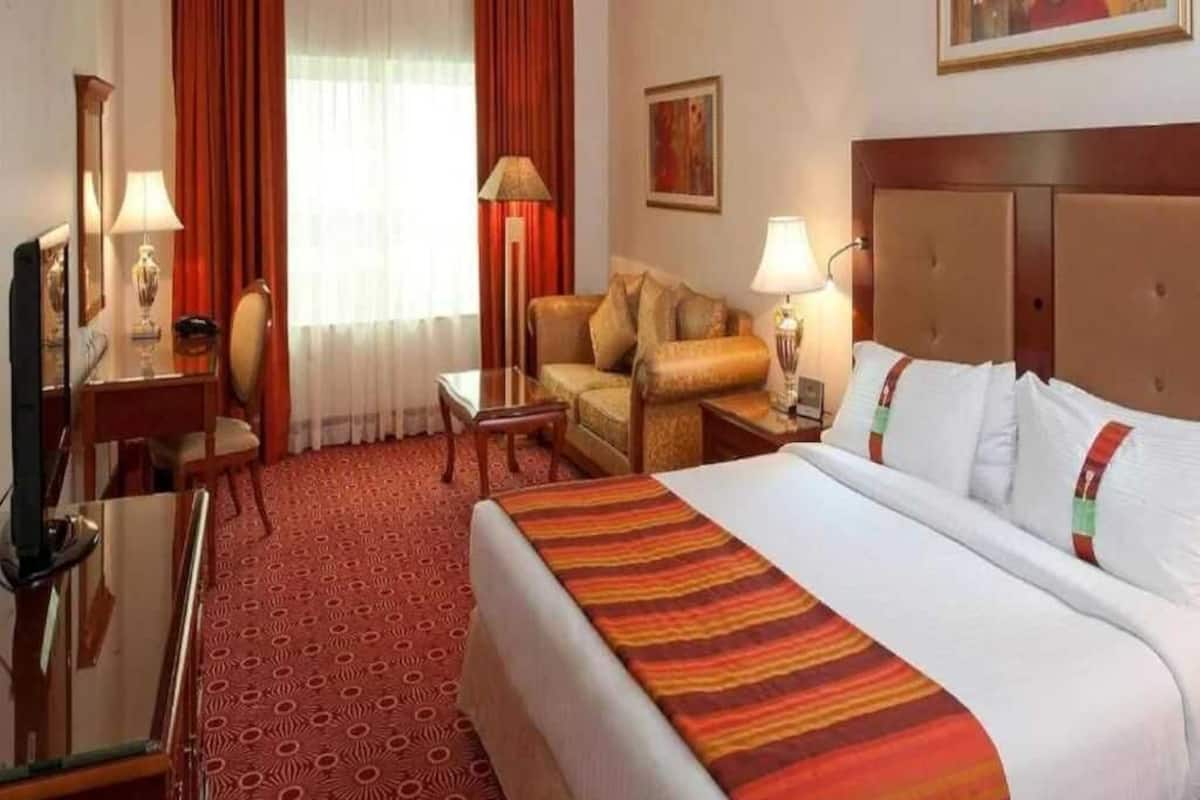 Une chambre d’hôtel avec un grand lit, un bureau, une chaise, un canapé et une télévision.
