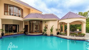 Una casa moderna con piscina, un patio cubierto y un amplio ventanal con vistas a la piscina.