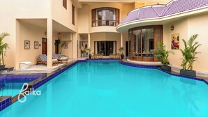 Una casa moderna con piscina, tumbonas y plantas en macetas.