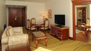 Een hotelkamer met een bank, fauteuils, een televisie, een kast en een spiegel.