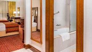 Een hotelkamer met een bed, een bureau, een stoel, een spiegel en een douche.