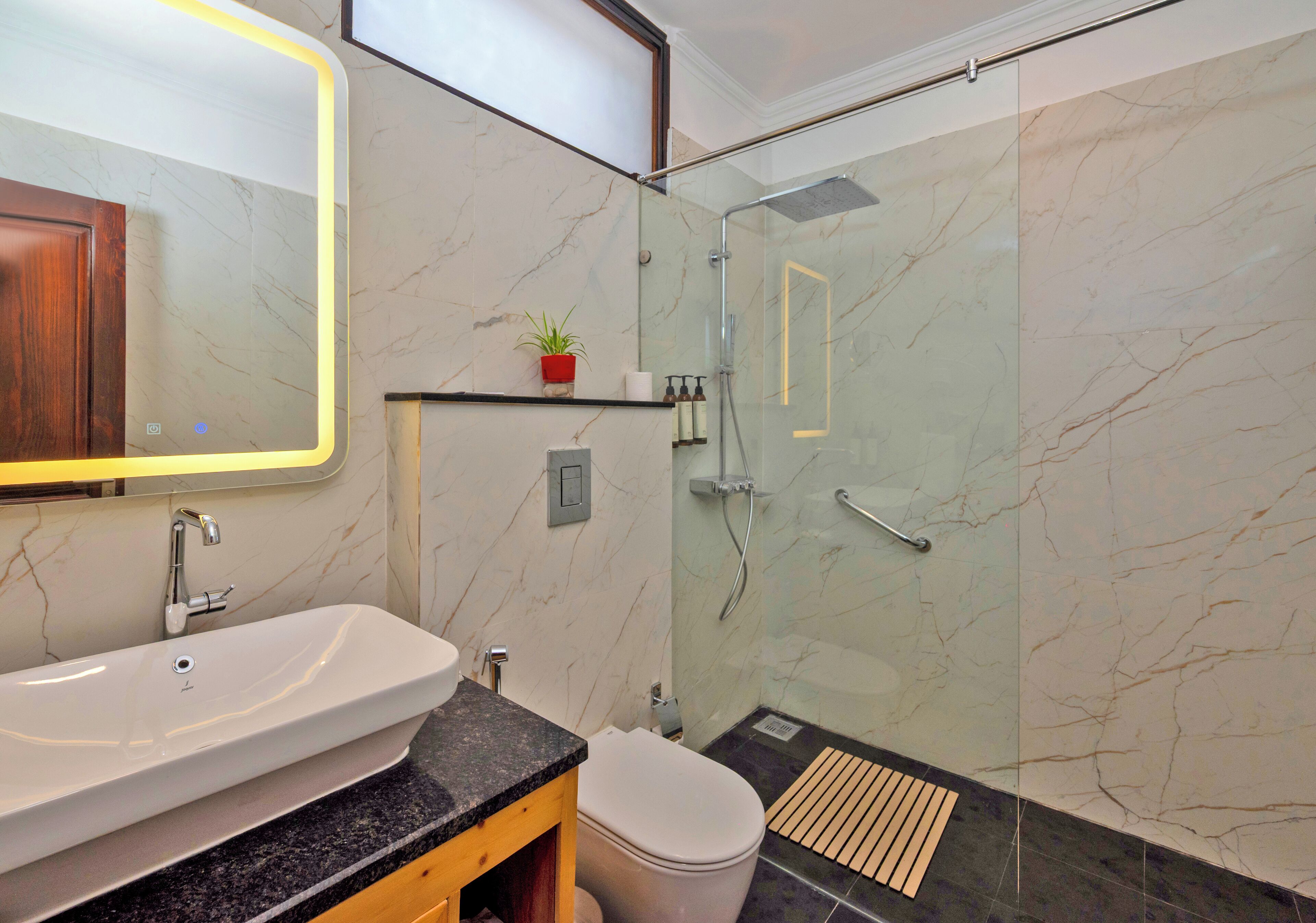Un bagno moderno con lavabo in marmo, cabina doccia in vetro e mobile bagno in legno.