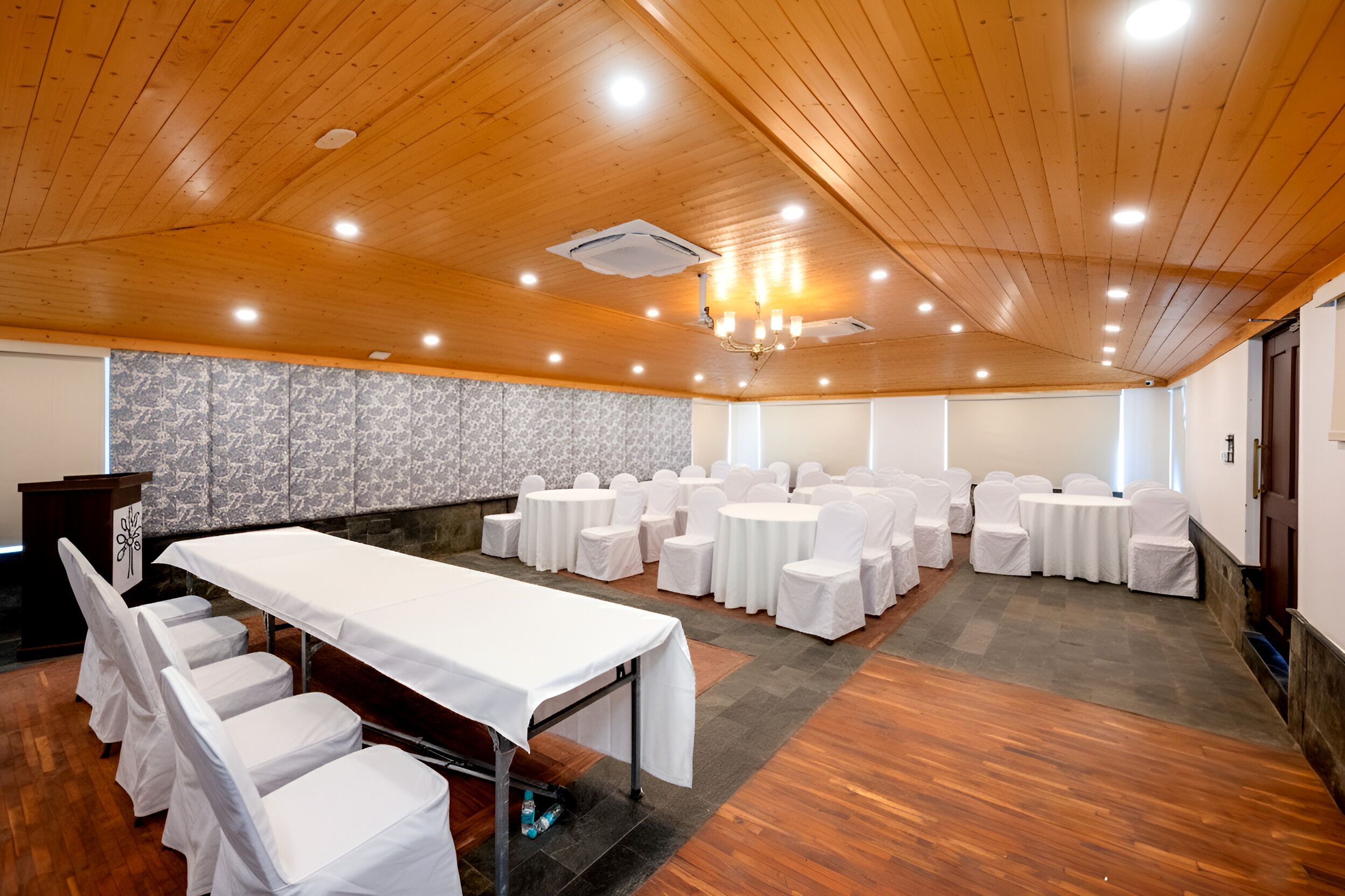 A conference room with a long table and chairs, wooden ceiling, and a chandelier.
