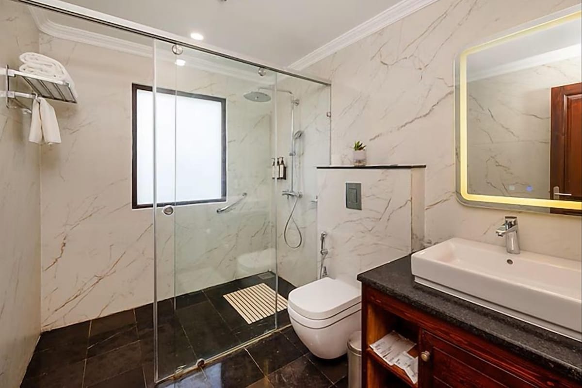 A modern bathroom with a glass-enclosed shower, a white toilet, and a marble-tiled floor.