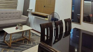 A modern living room with a sofa, dining table, chairs, and a ceiling fan. - Jewel's Homey Place -2br in a Resort-like Condo (Pasig)