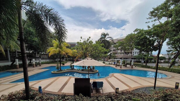 A swimming pool with a central fountain, surrounded by palm trees and a gazebo. - Jewel's Homey Place -2br in a Resort-like Condo (Pasig)