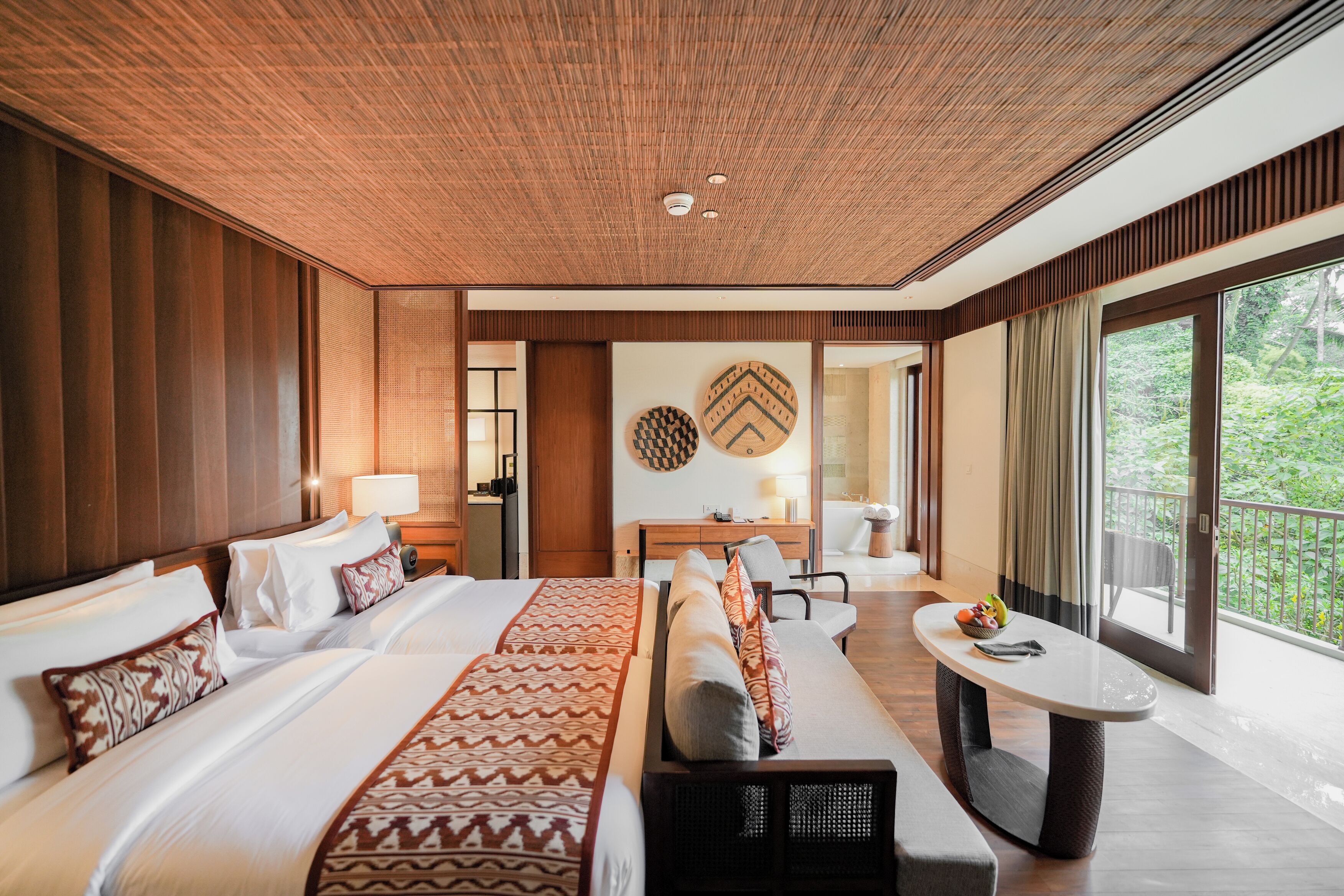 Une chambre d’hôtel avec un grand lit, un bureau, une chaise et une vue sur la verdure.
