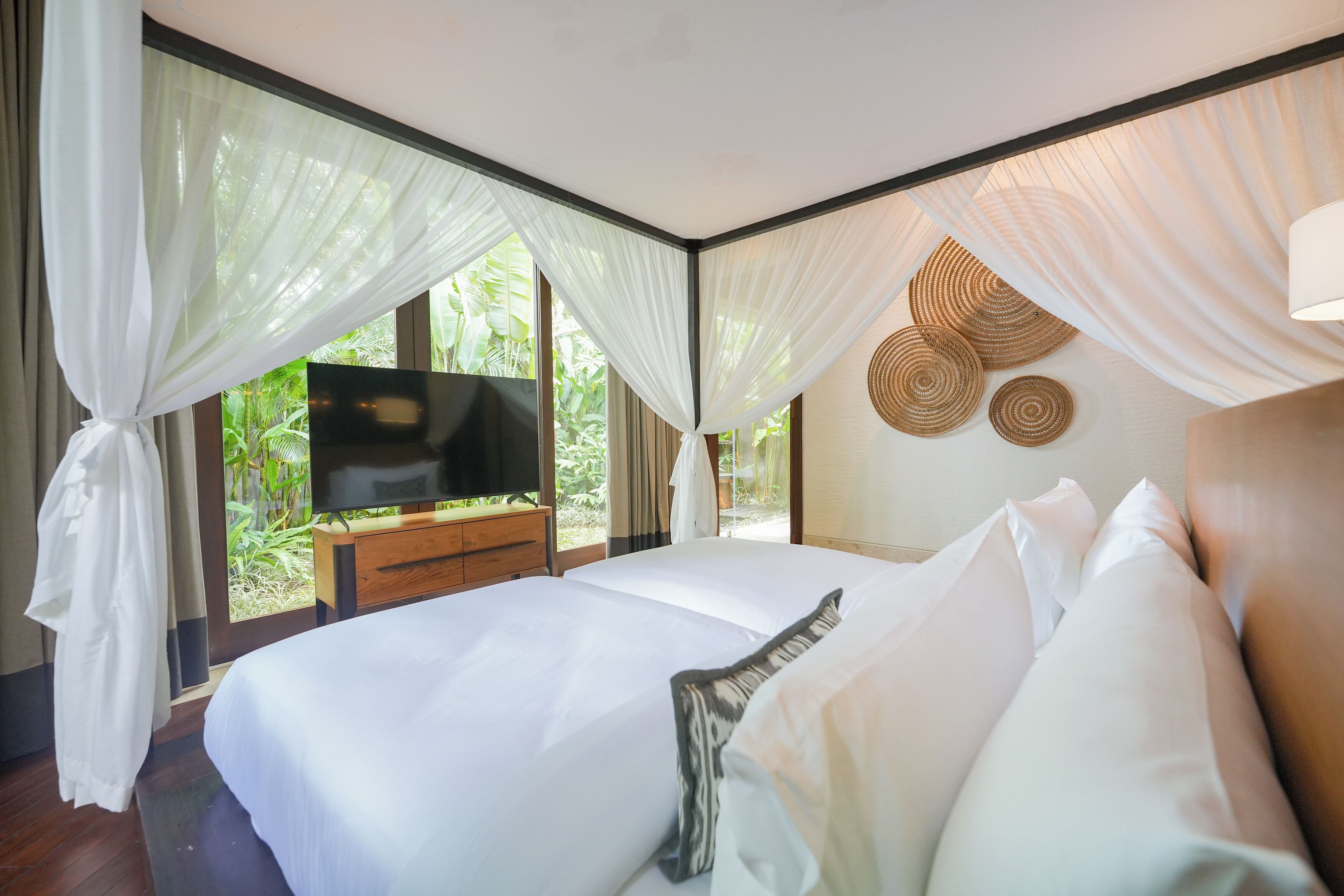 Une chambre avec un grand lit, une télévision et une vue sur la verdure.