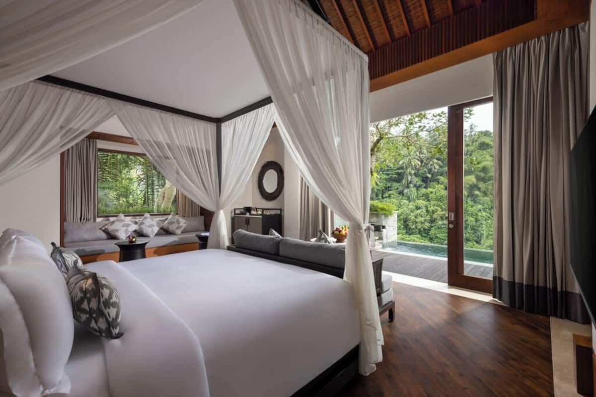 Un dormitorio espacioso con una cama grande, vistas a exuberante vegetación y un balcón.