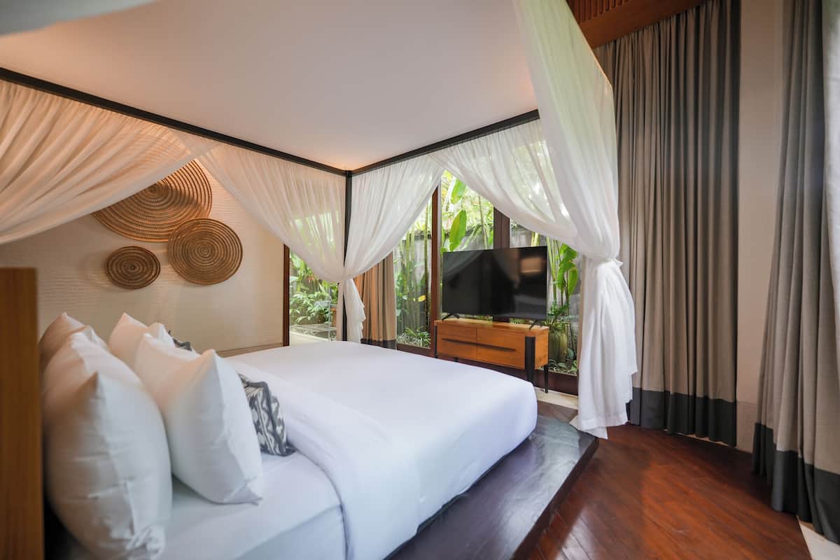 Un dormitorio con cama, cortinas, televisor y cómoda de madera.