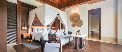 A bedroom with a canopy bed, a sofa, a chair, a round table, and a wall with circular patterns.