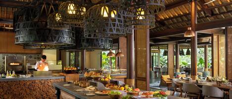 A restaurant with a long counter, wooden logs, and hanging lanterns.