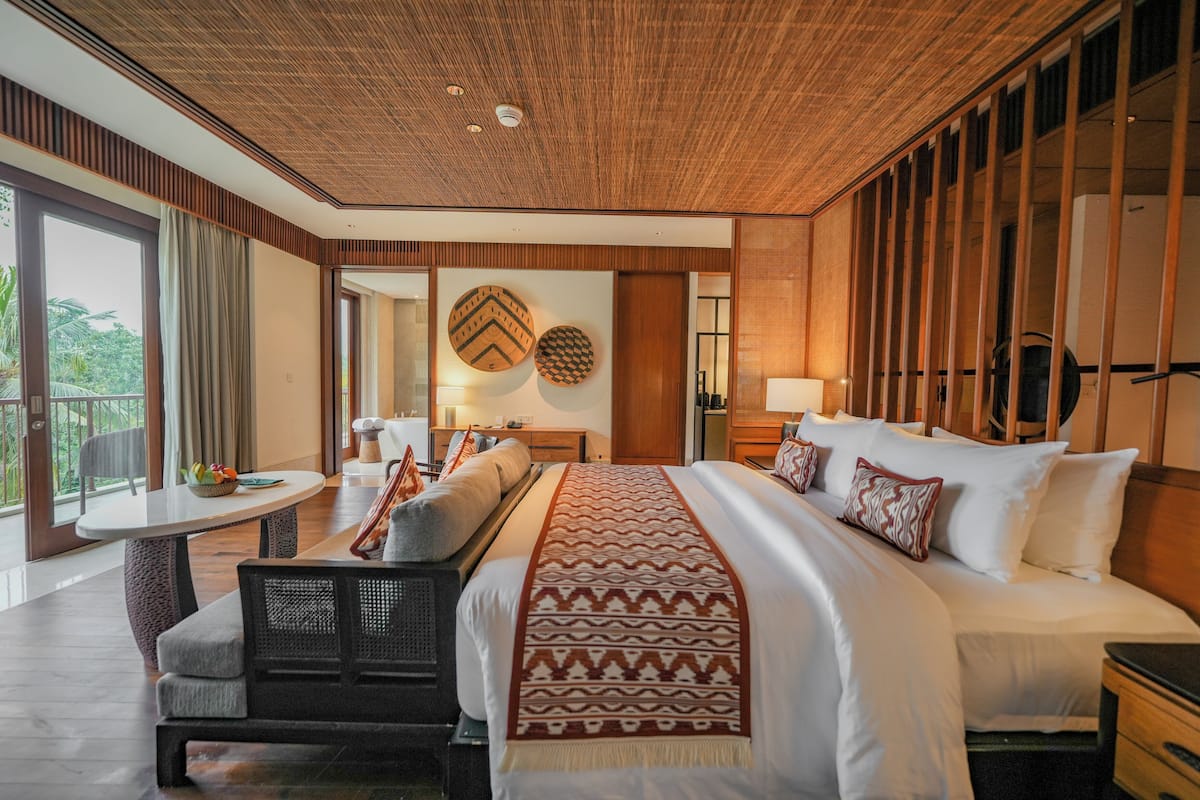 Una habitación de hotel con una cama grande, un comedor y vistas al exterior.