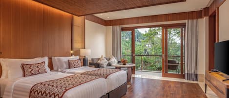 Habitación de hotel con una cama grande, televisión, balcón y vistas a árboles, además de suelo de madera.