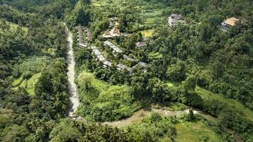 An aerial view of a resort with multiple bungalow-style buildings surrounded by lush greenery and terraced fields.