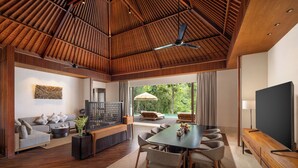 Amplia sala de estar con techo de madera, un televisor de pantalla plana grande, una mesa de comedor con sillas, un sofá y vistas al exterior.