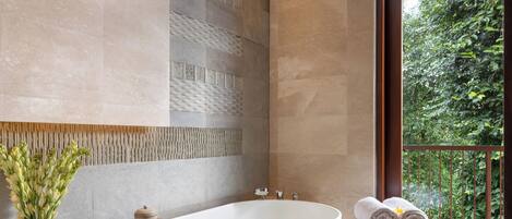 A modern bathroom with a freestanding bathtub, a wooden tray, and a vase of flowers.