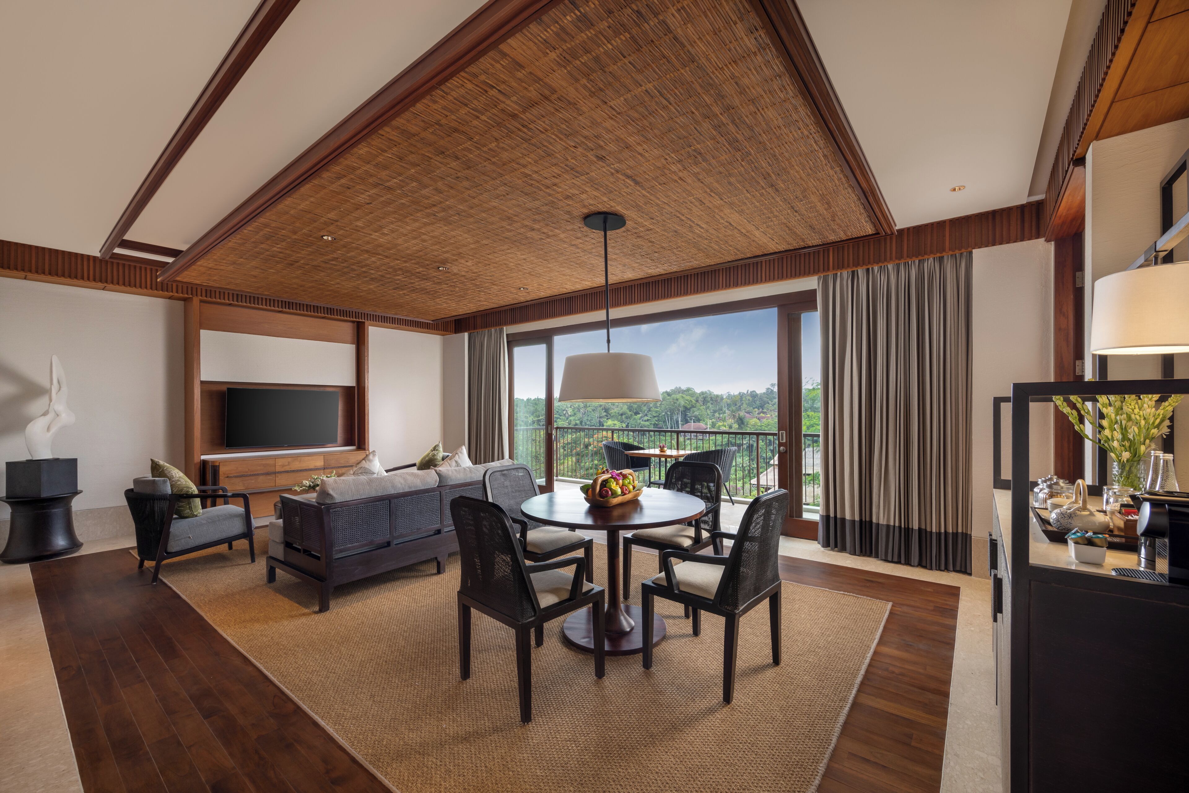 A modern living room with a large TV, a sofa, a dining table with chairs, and a balcony with curtains.