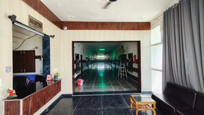 Ein Hotel-Empfangsbereich mit einer Rezeption, einem Empfangsschild, einer Treppe zu den oberen Etagen und Blick auf den Korridor.
