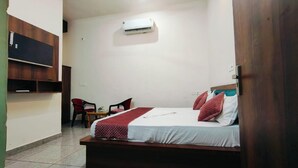 Ein Schlafzimmer mit einem Bett, einem Sessel, einem kleinen Tisch und einer Klimaanlage.