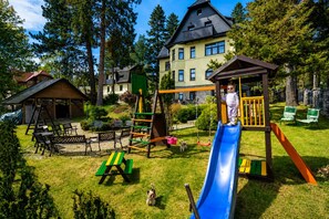 Ein Spielplatz mit Rutsche, Schaukeln und einer Kletterkonstruktion.