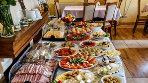 Una mesa de buffet con diversos alimentos, como carnes, quesos y ensaladas, en un comedor con sillas y una mesa.