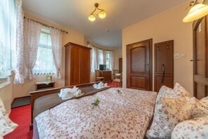Ein Hotelzimmer mit Bett, Holzschrank, Schreibtisch und Spiegel.