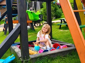 Un niño jugando en un parque infantil de madera con tobogán y columpios.
