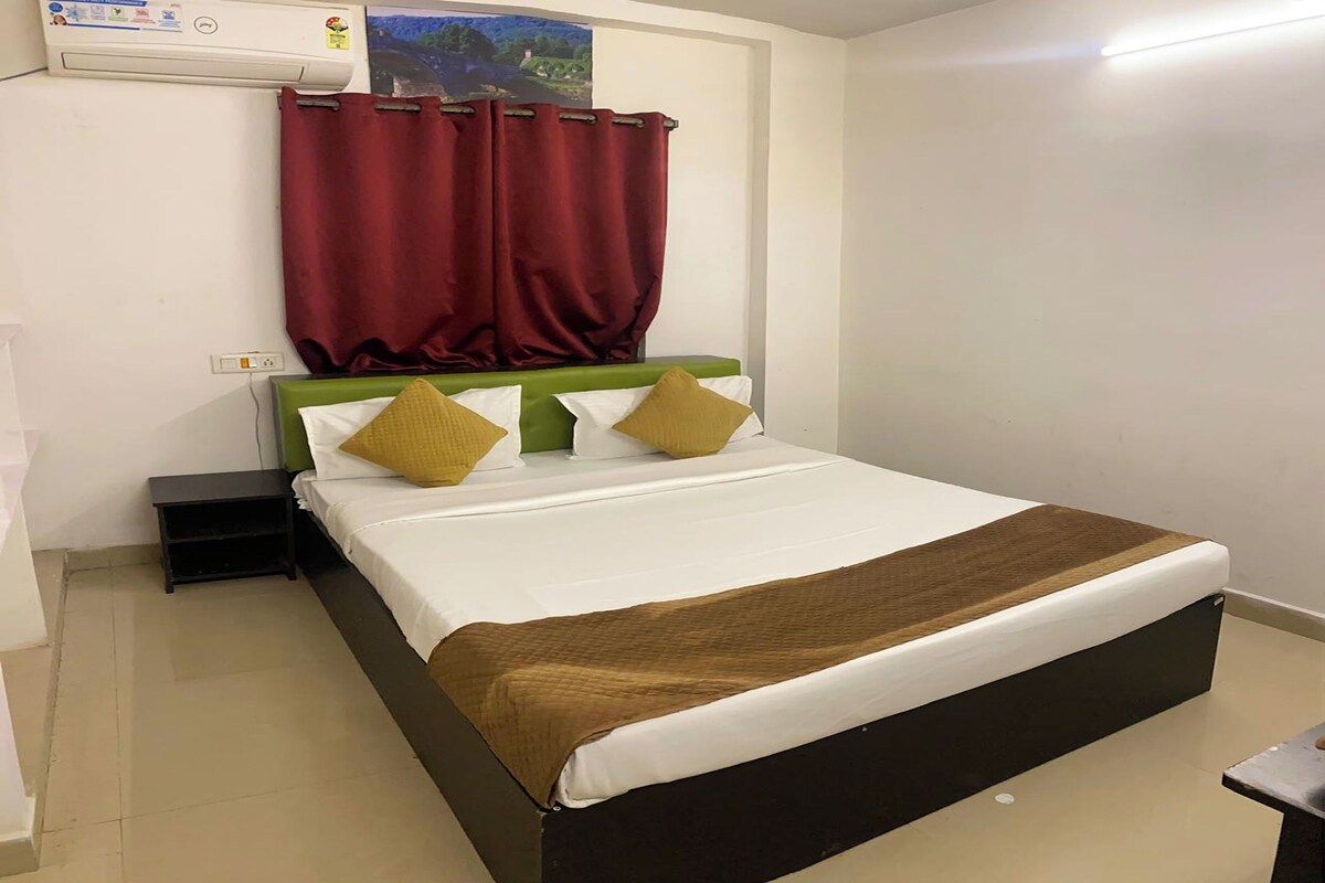 Una cama bien hecha con un cubrecolcha marrón, un cabecero verde y dos almohadas color mostaza.