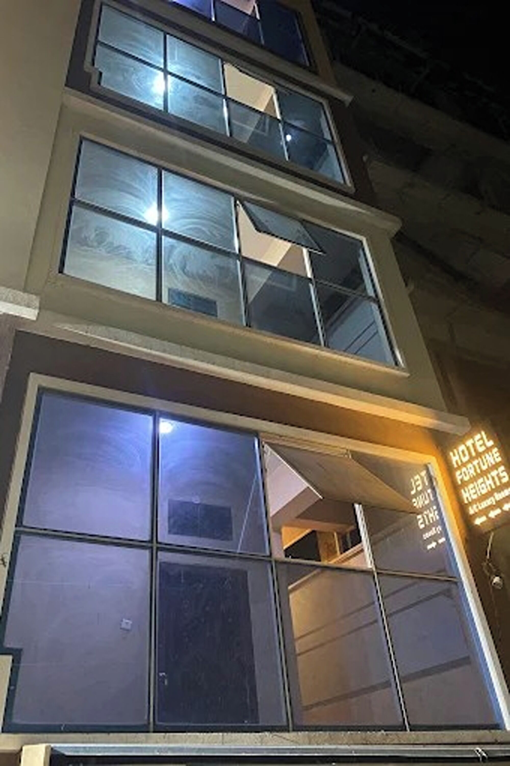 Ein mehrstöckiges Gebäude mit großen Fenstern und einem Schild, das es als Hotel Fortune Heights kennzeichnet.