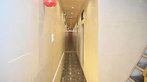 A corridor with a polished marble floor, wooden ceiling, and a fire extinguisher mounted on the wall.