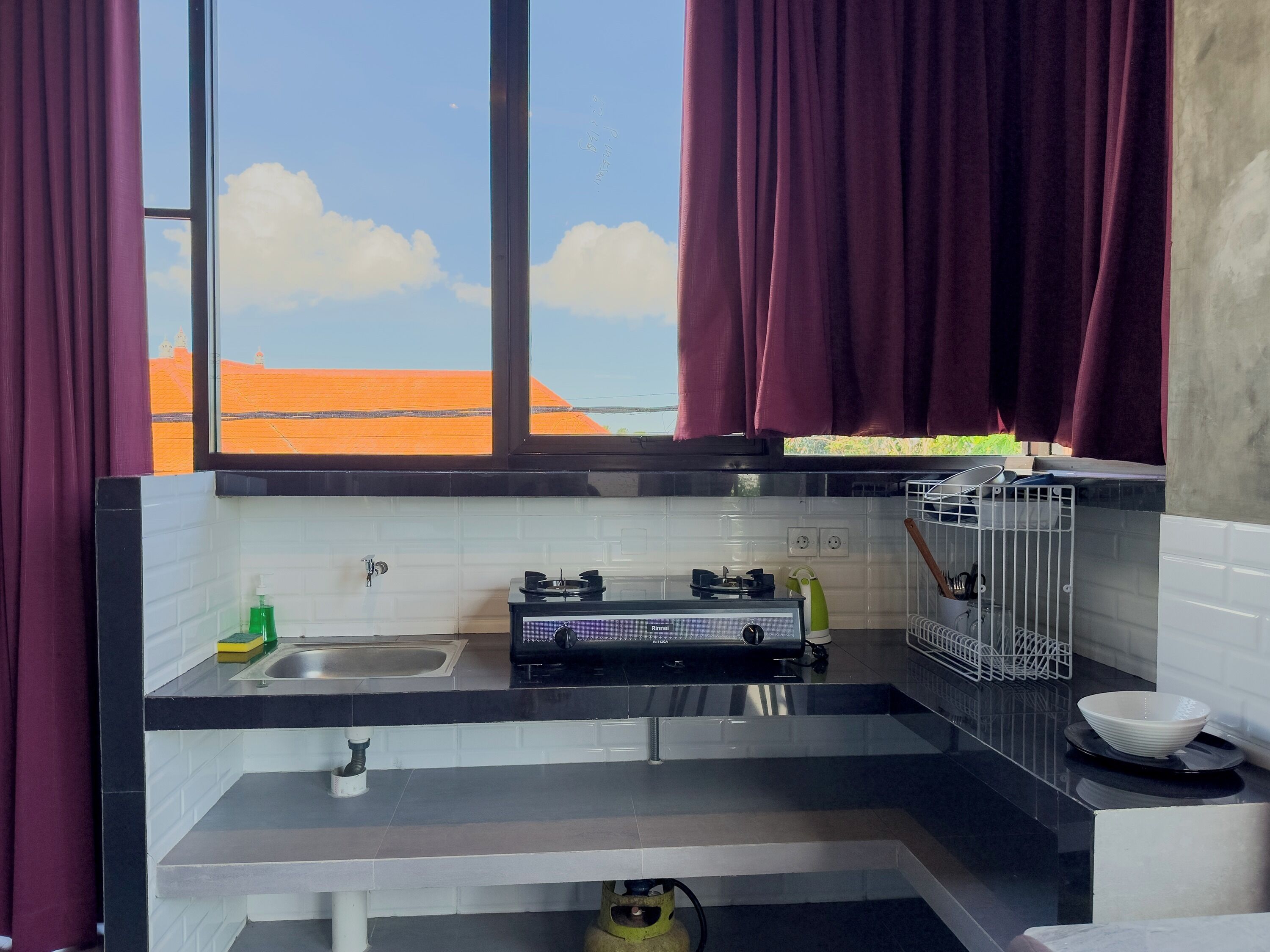 A compact kitchen with a sink, stove, and a view of the orange landscape.