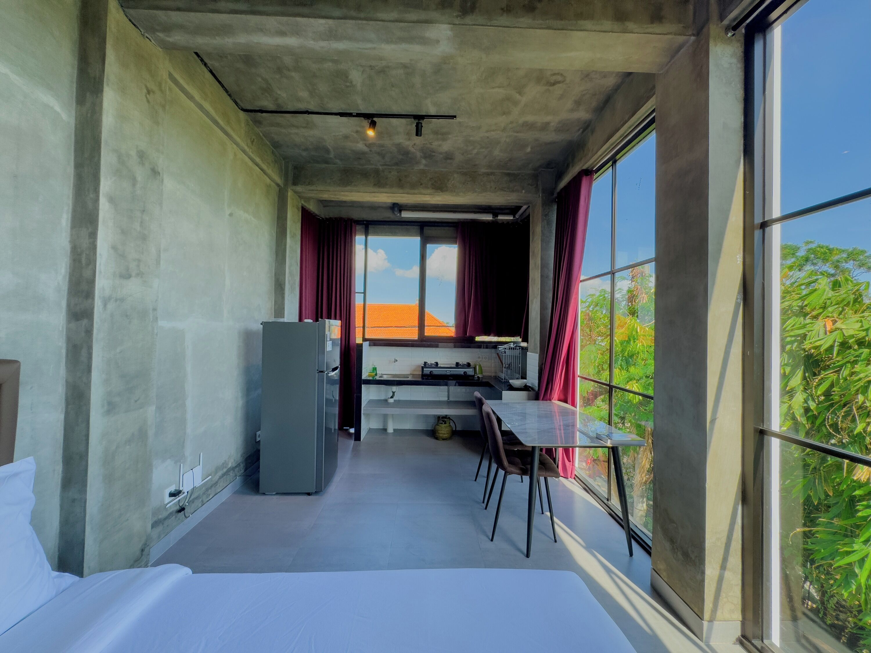 Una cocina compacta con refrigerador, una mesa de comedor y un ventanal con cortinas.