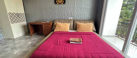 A modern bedroom with a large bed, a wooden nightstand, a decorative wall piece, and a view of the outdoors.