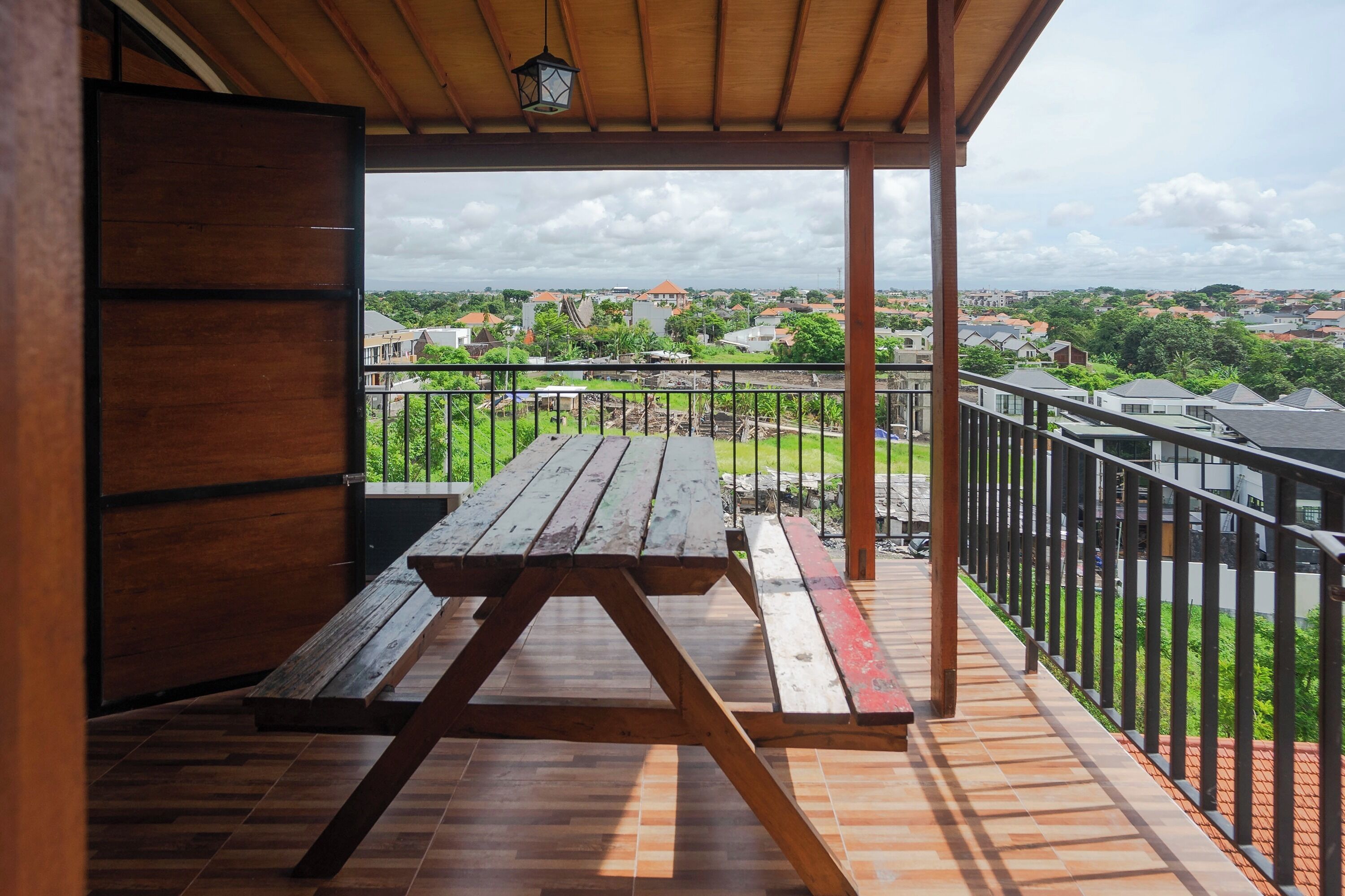 A covered outdoor area with a wooden picnic table and a view of a residential neighborhood.