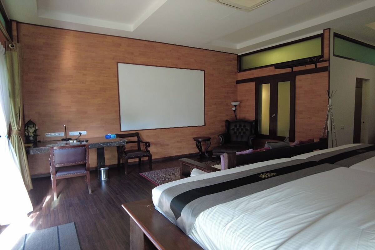A hotel room with a large bed, a desk with a chair, a television, and a small table.