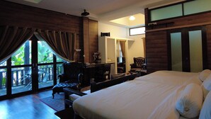 A spacious bedroom with a large bed, a desk, and a chair. There is a sliding glass door leading to a balcony.