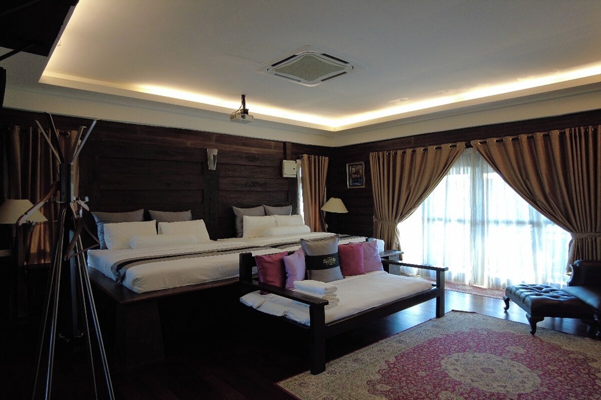 A hotel room with two beds, a large window with curtains, a standing lamp, and a wooden headboard.