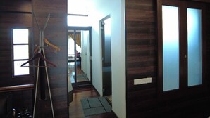 A hallway with wooden paneling, a coat rack, and a bed in the background.