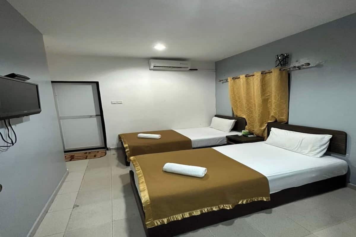 A hotel room with two beds, a TV, an air conditioner, and a curtain.