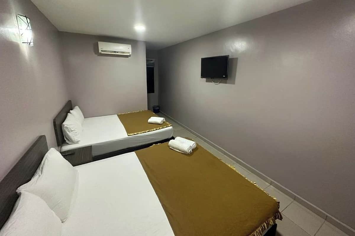 A hotel room with two beds, a TV, and an air conditioning unit.