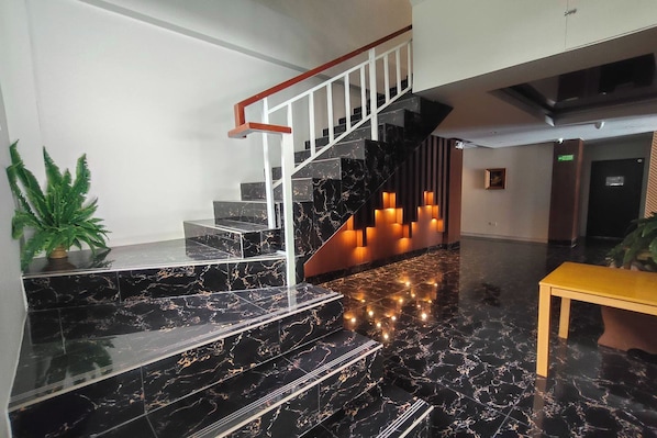 Un escalier moderne avec des marches en marbre noir et une rampe blanche, menant à un niveau inférieur.