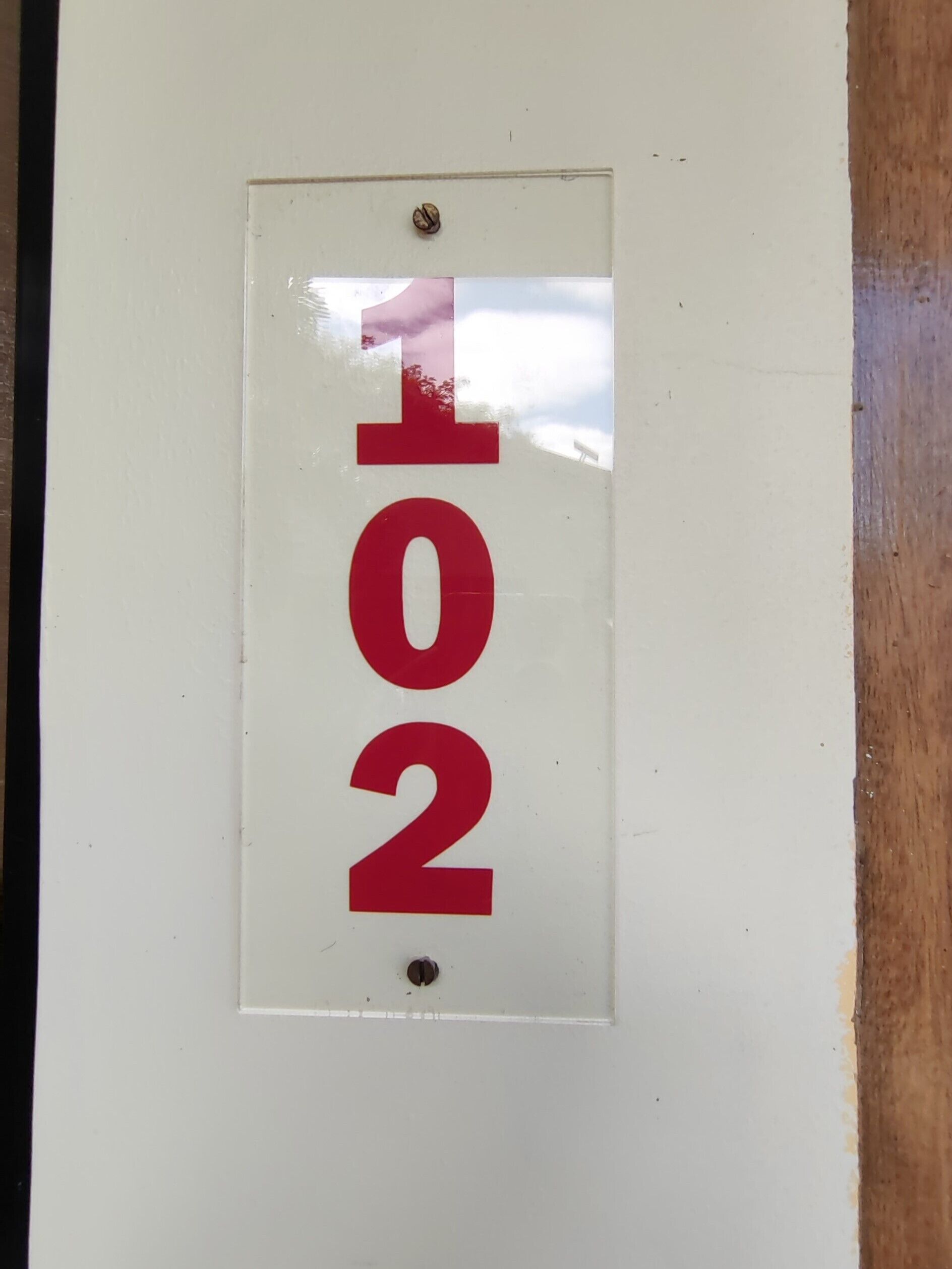 A white sign with red numbers "101" and "2" mounted on a wall.