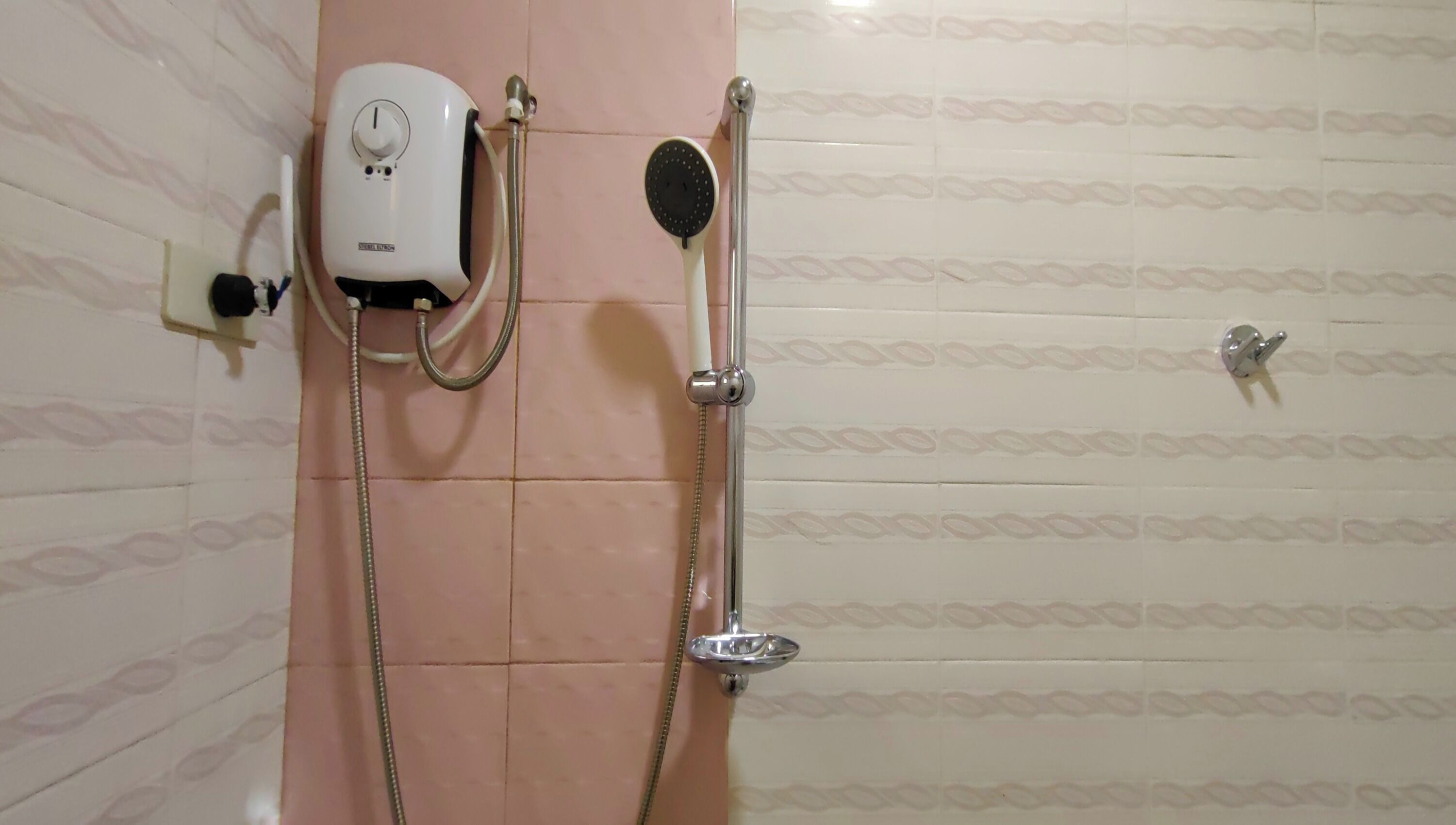 Ducha con cabezal de ducha de mano y mando de control en la pared.