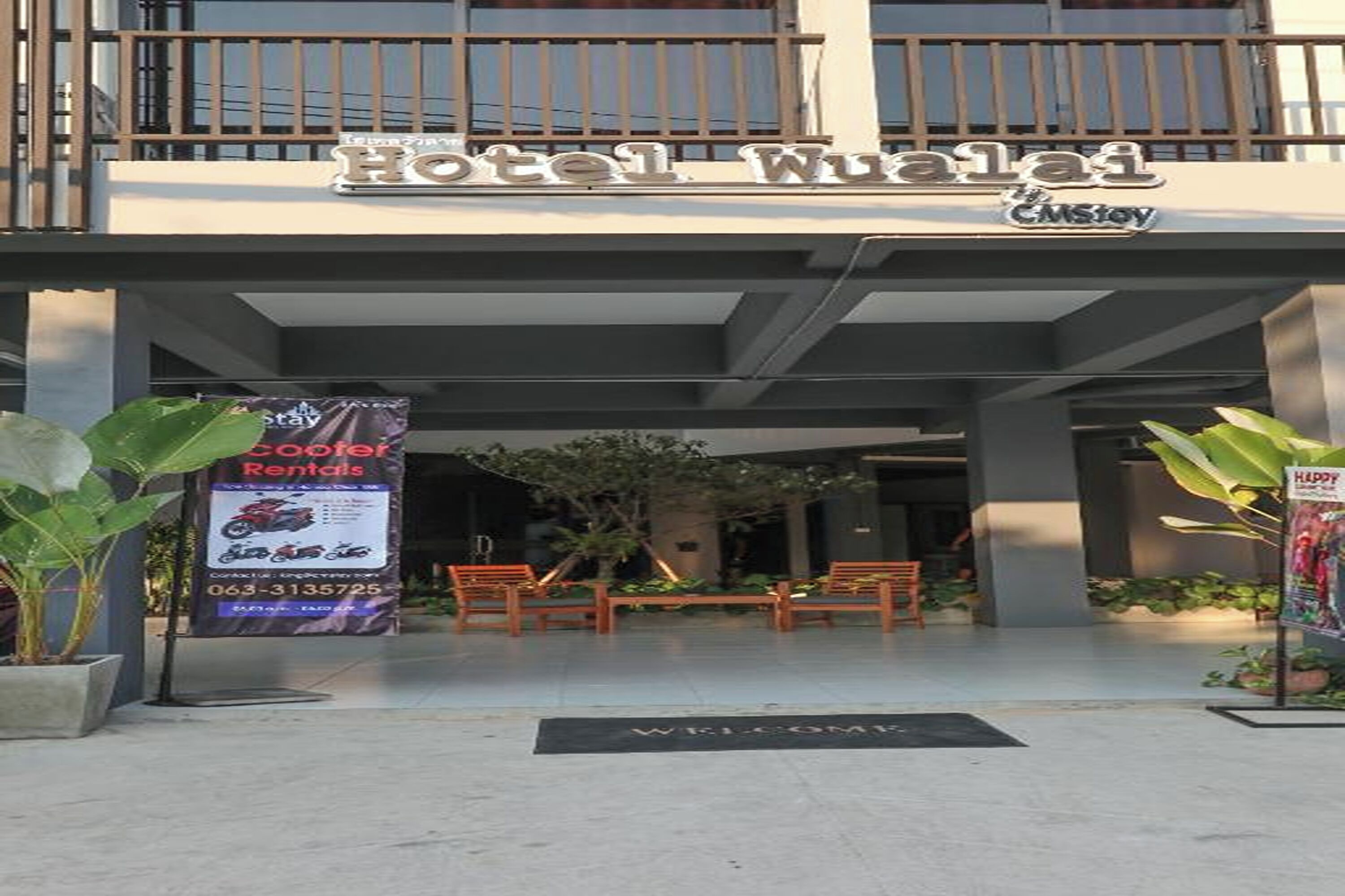 The entrance to Hotel Wualai with a balcony, a welcome mat, and a sign for Happy Rentals.