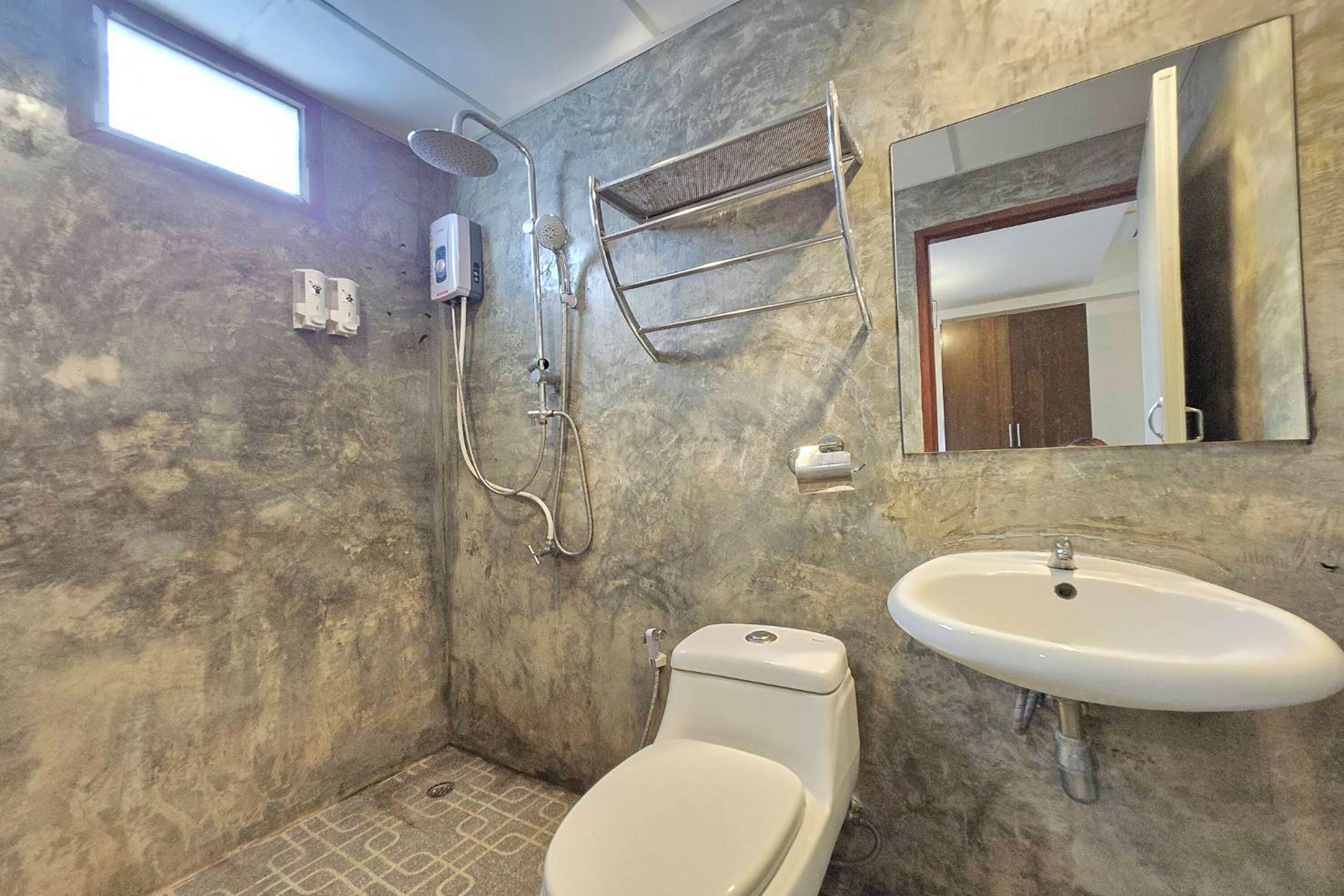 A bathroom with a toilet, sink, shower, and a mirror.